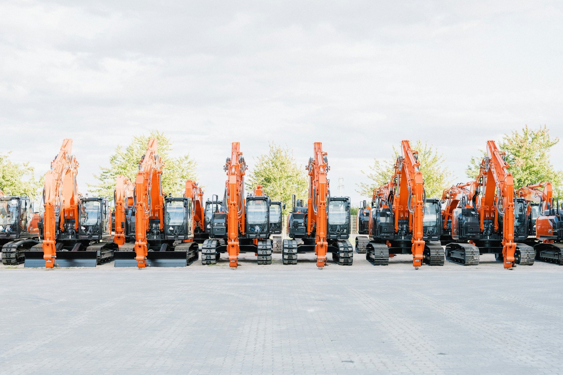A row of new orange excavators lined up on an equipment yard